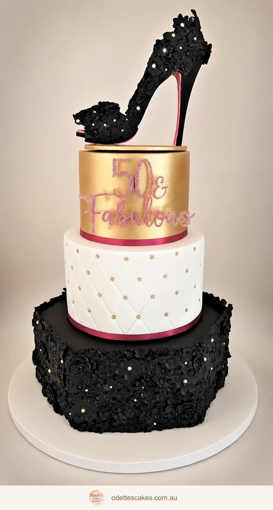 Three-tier black, white and gold birthday cake with a sparkling black high-heel topper