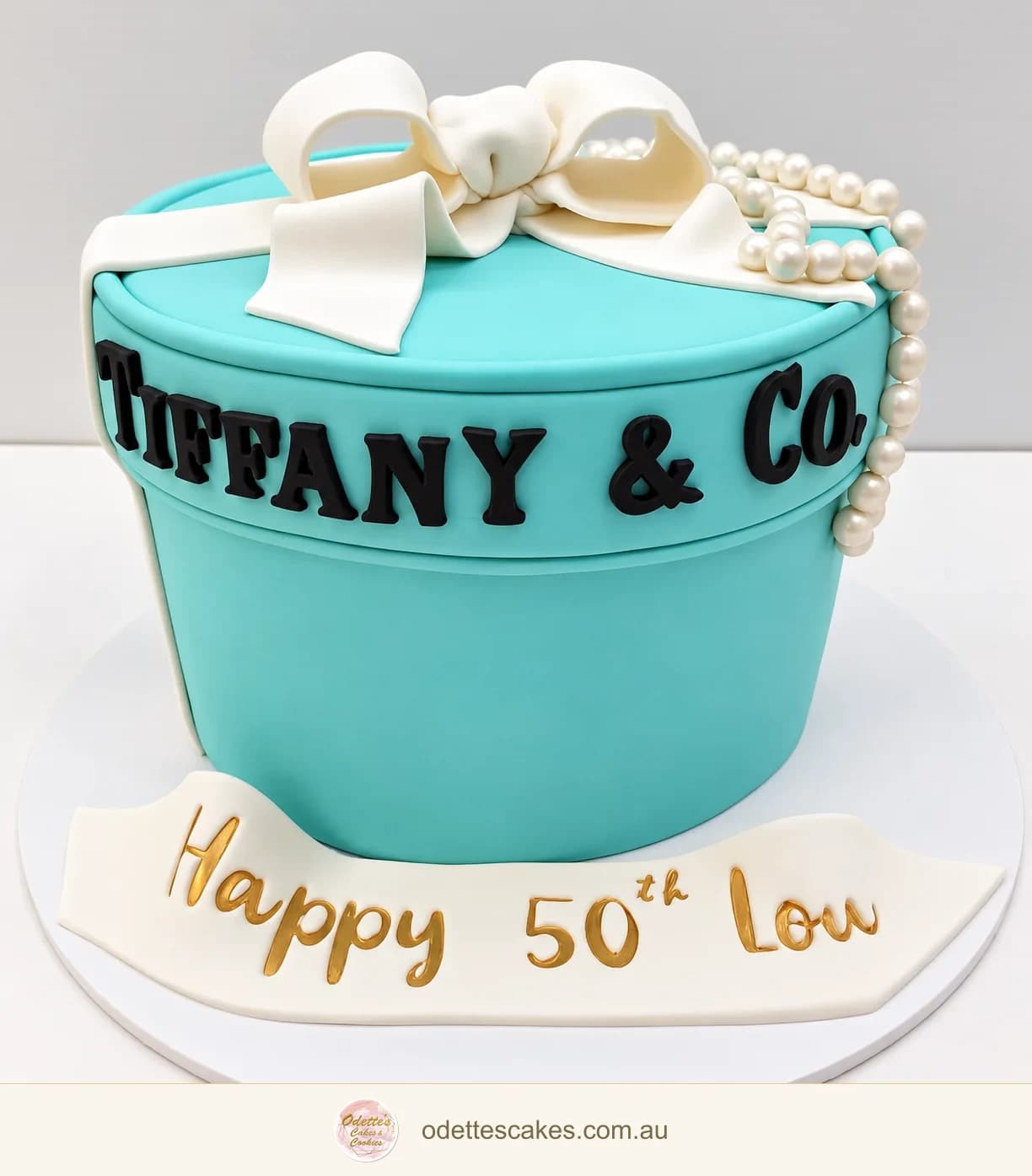 Turquoise gift-box birthday cake with a white ribbon bow, pearls and Tiffany-inspired lettering
