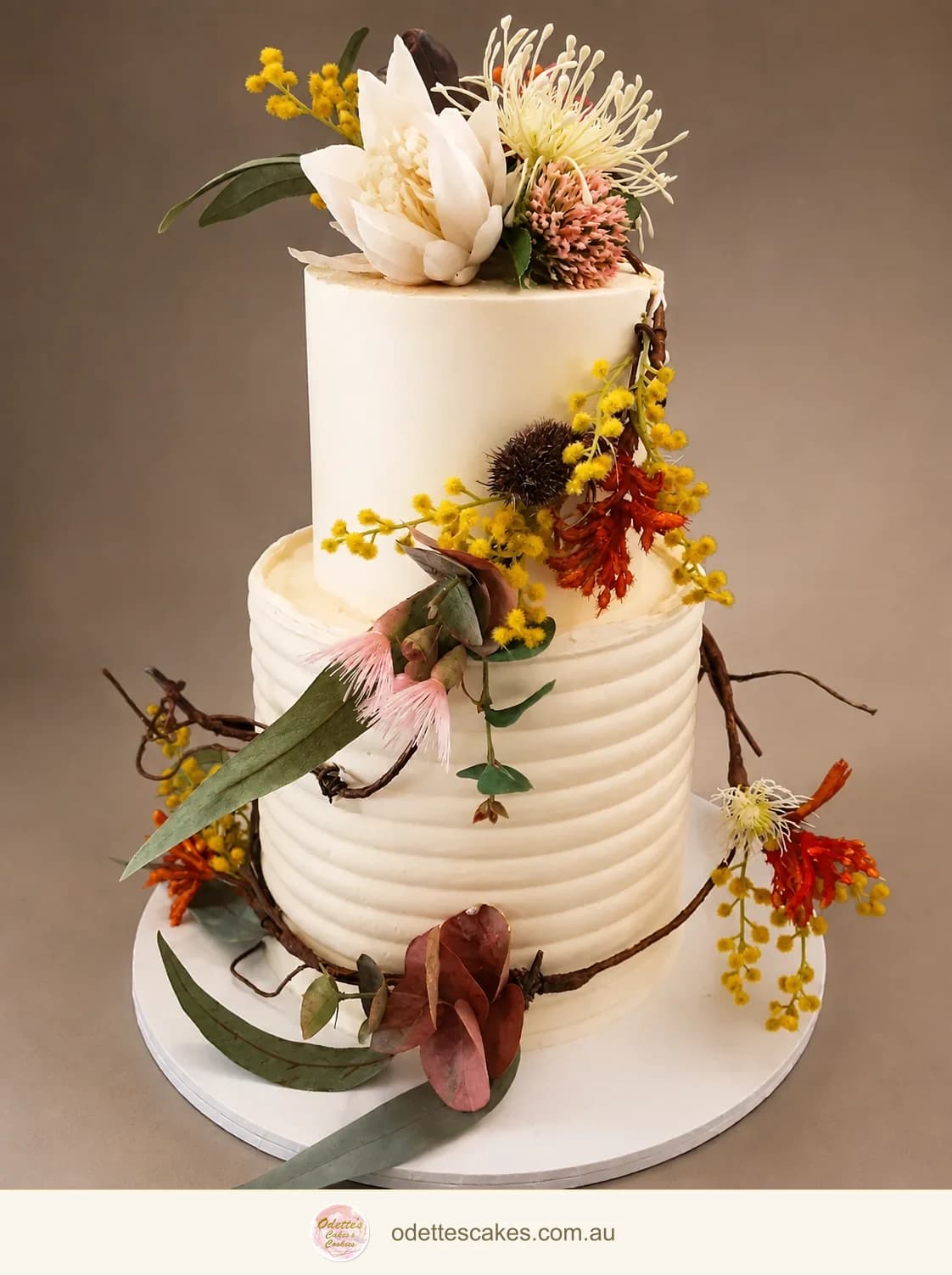 Two-tier white wedding cake with rippled buttercream, proteas, native flowers and eucalyptus