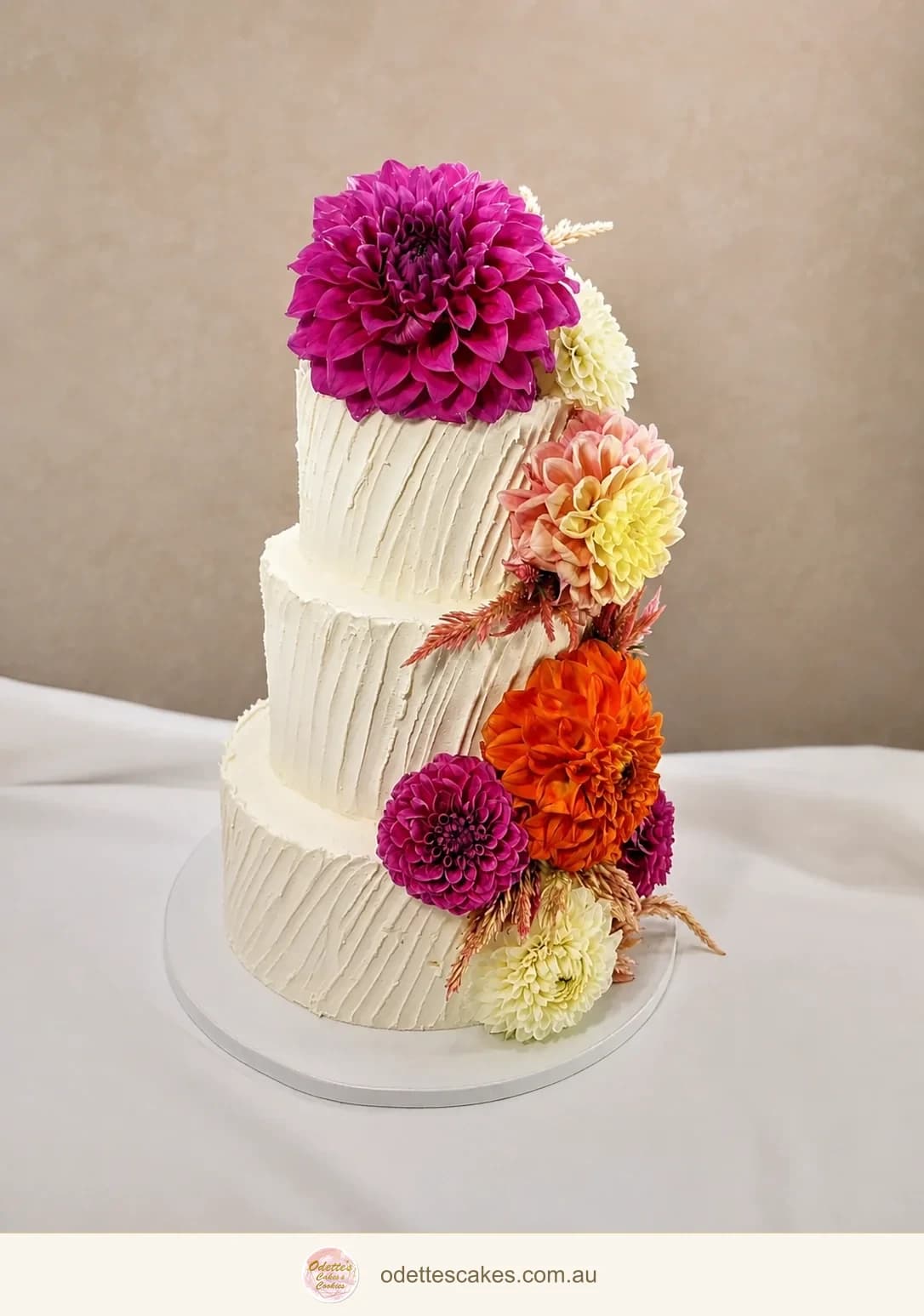 Two-tier ivory wedding cake with textured buttercream and vivid pink, orange and yellow flowers