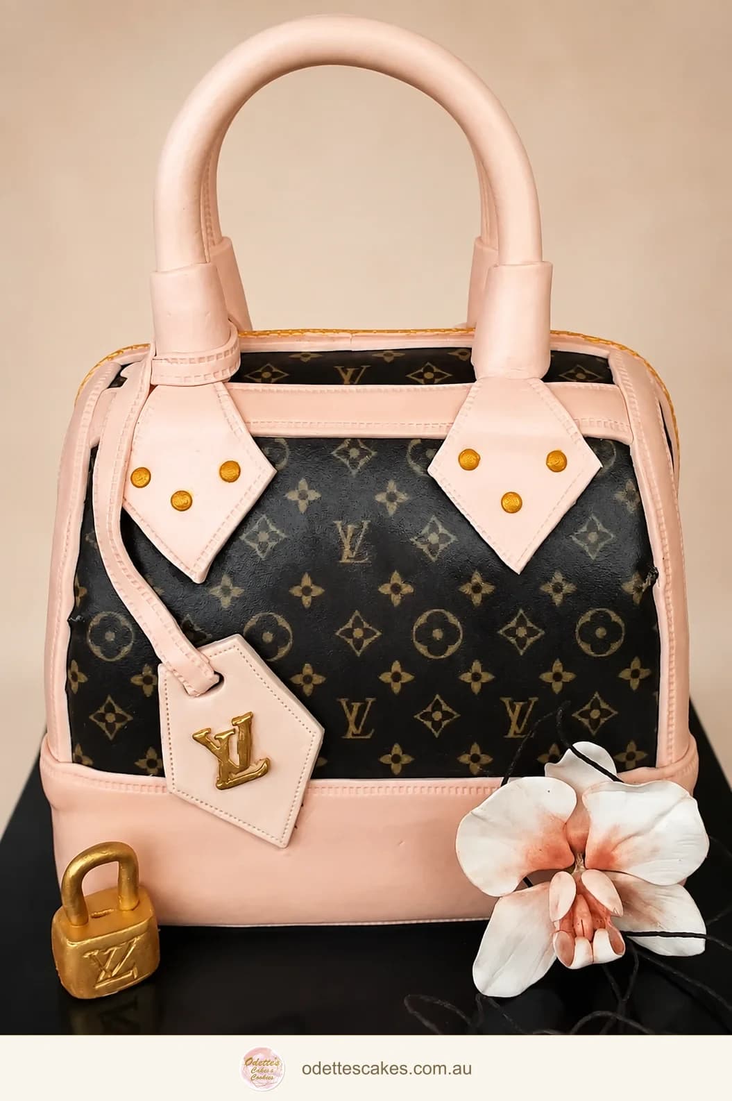 Sculpted handbag birthday cake with pale pink handles, a monogram pattern and a sugar flower
