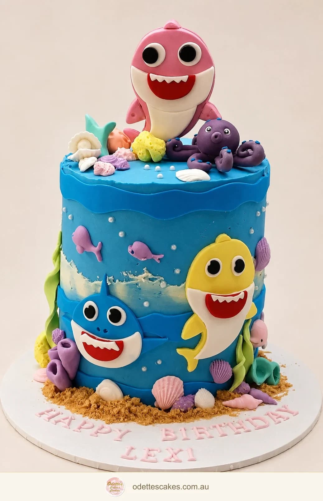 Blue Baby Shark birthday cake with colourful sea creatures and a pink shark topper